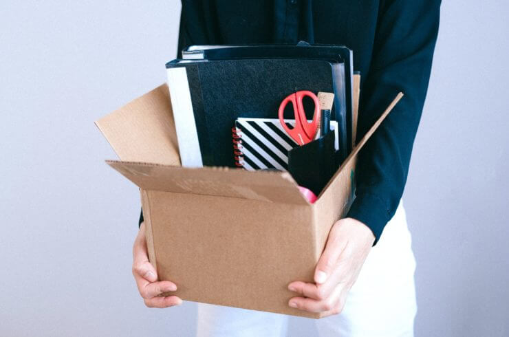 a person holding a box with office supplies